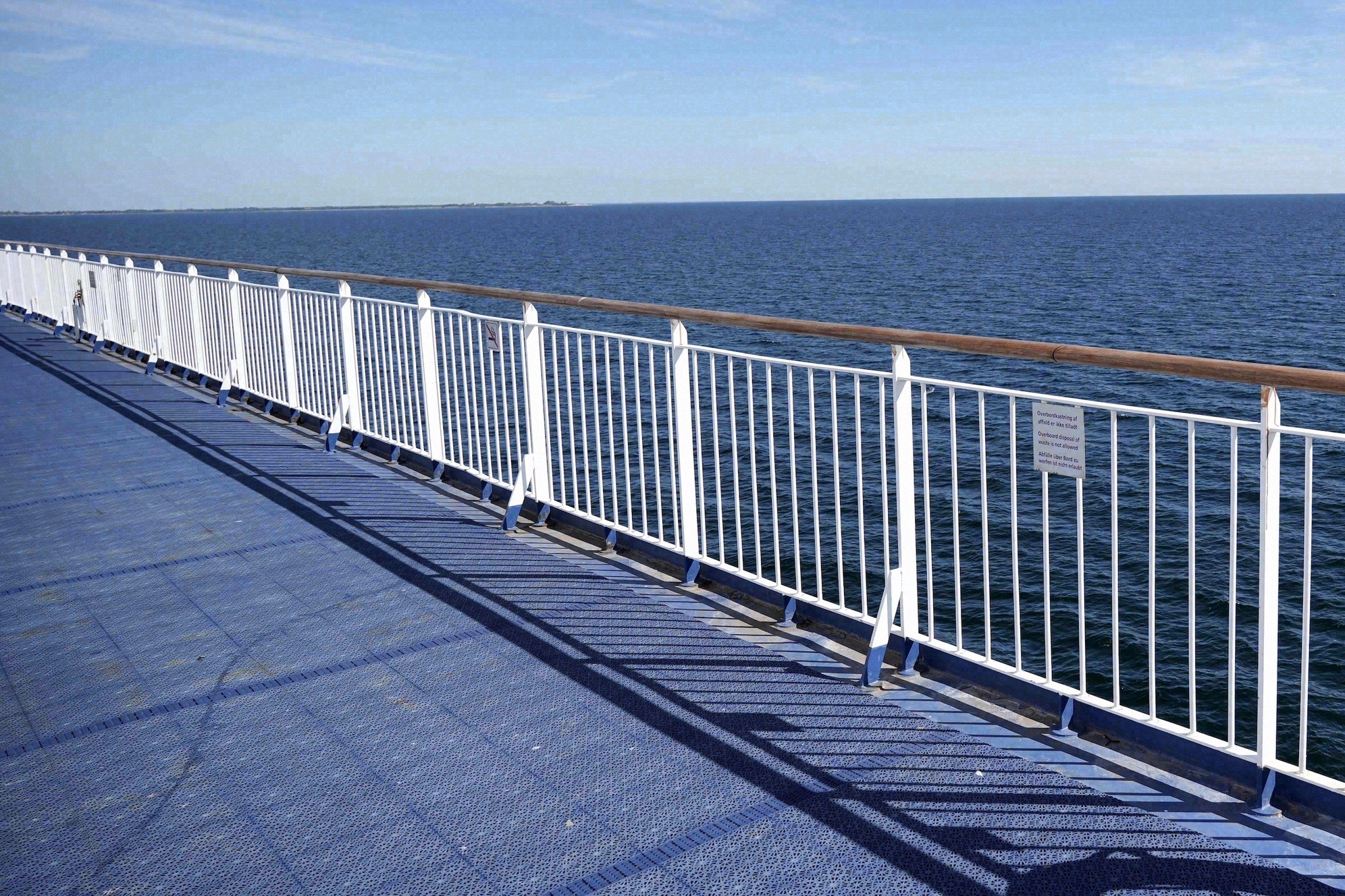 Blick über das Außendeck einer Fähre mit weißer Reling auf das offene Meer